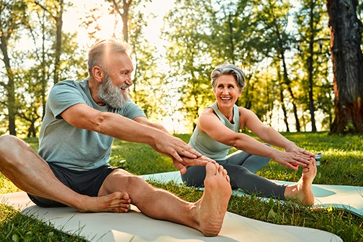 Älteres Paar macht Yoga in der Natur.