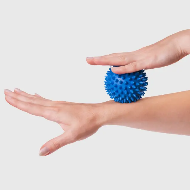 Frauenhände rollen Massageball über das Handgelenk.
