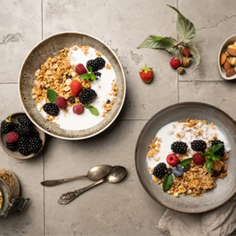 Zwei Schüsseln Joghurt mit Müsli auf dem Tisch.