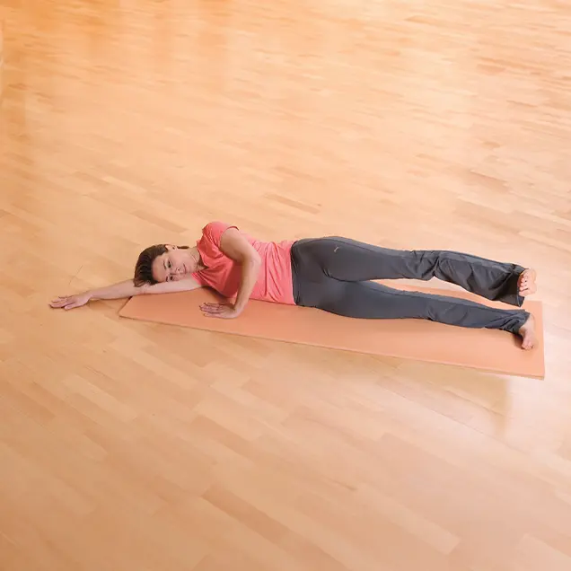 Frau liegt ausgestreckt auf der Seite auf einer Yogamatte.