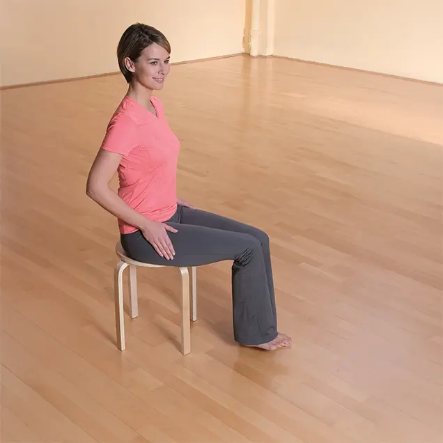 Frau in Sportkleidung sitzt auf einem Hocker.